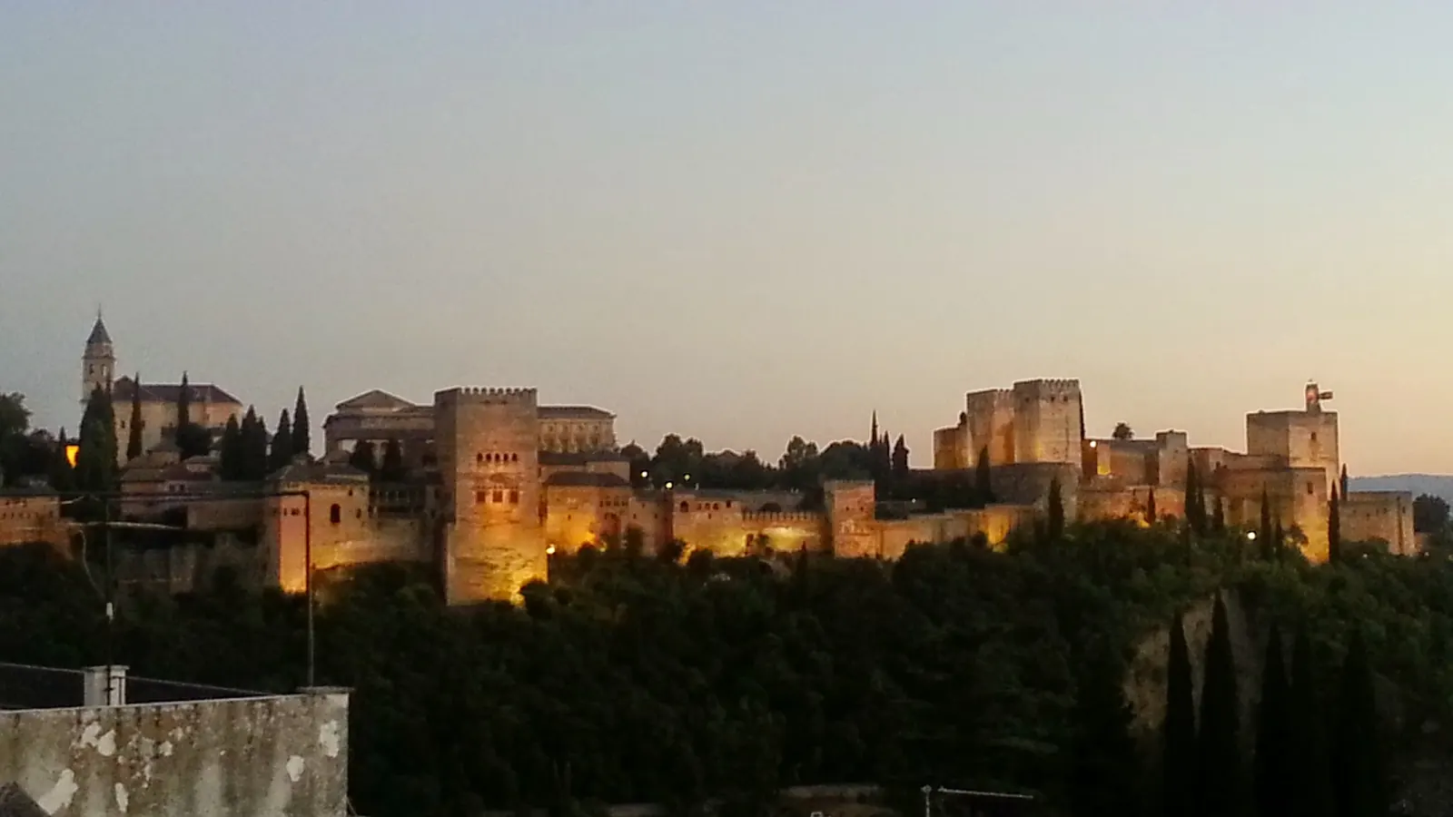 The Alhambra lit up at dusk, seen from the Sacromonte hillside